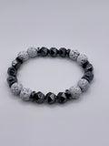 Bracelet with gray and black beads on a light gray background