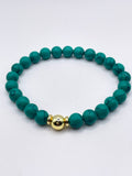 Teal beaded bracelet with a gold accent on a white background