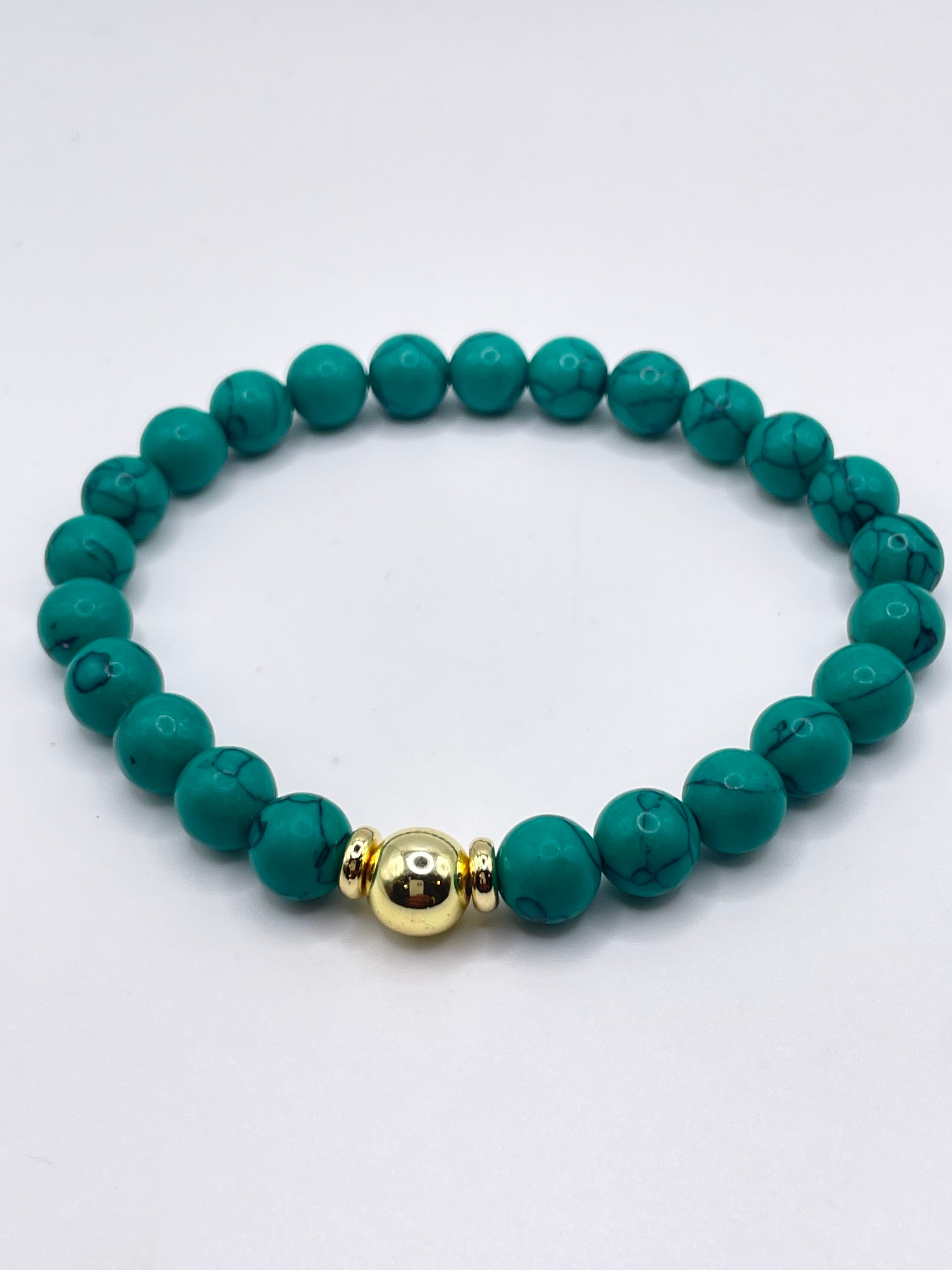 Teal beaded bracelet with a gold accent on a white background