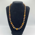 Beaded necklace on a black velvet stand with a white background