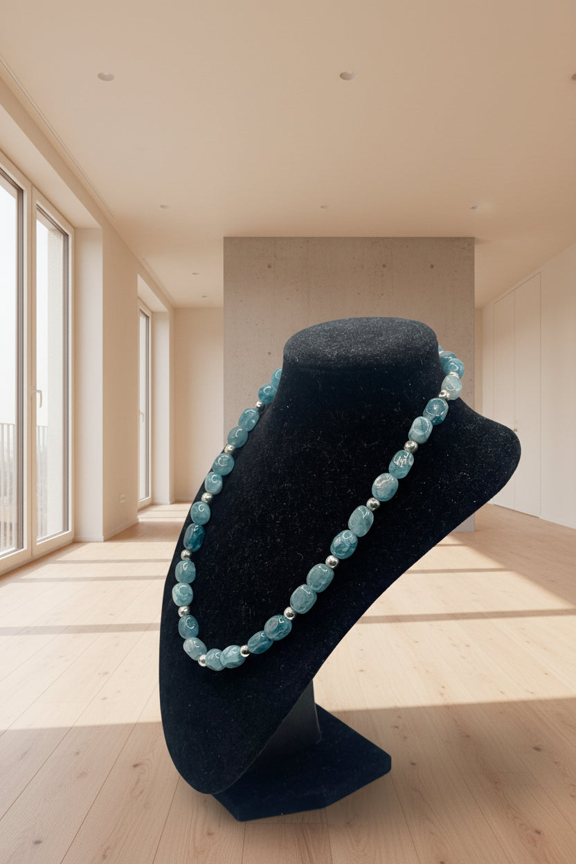 Blue beaded necklace on a black mannequin bust against a white background