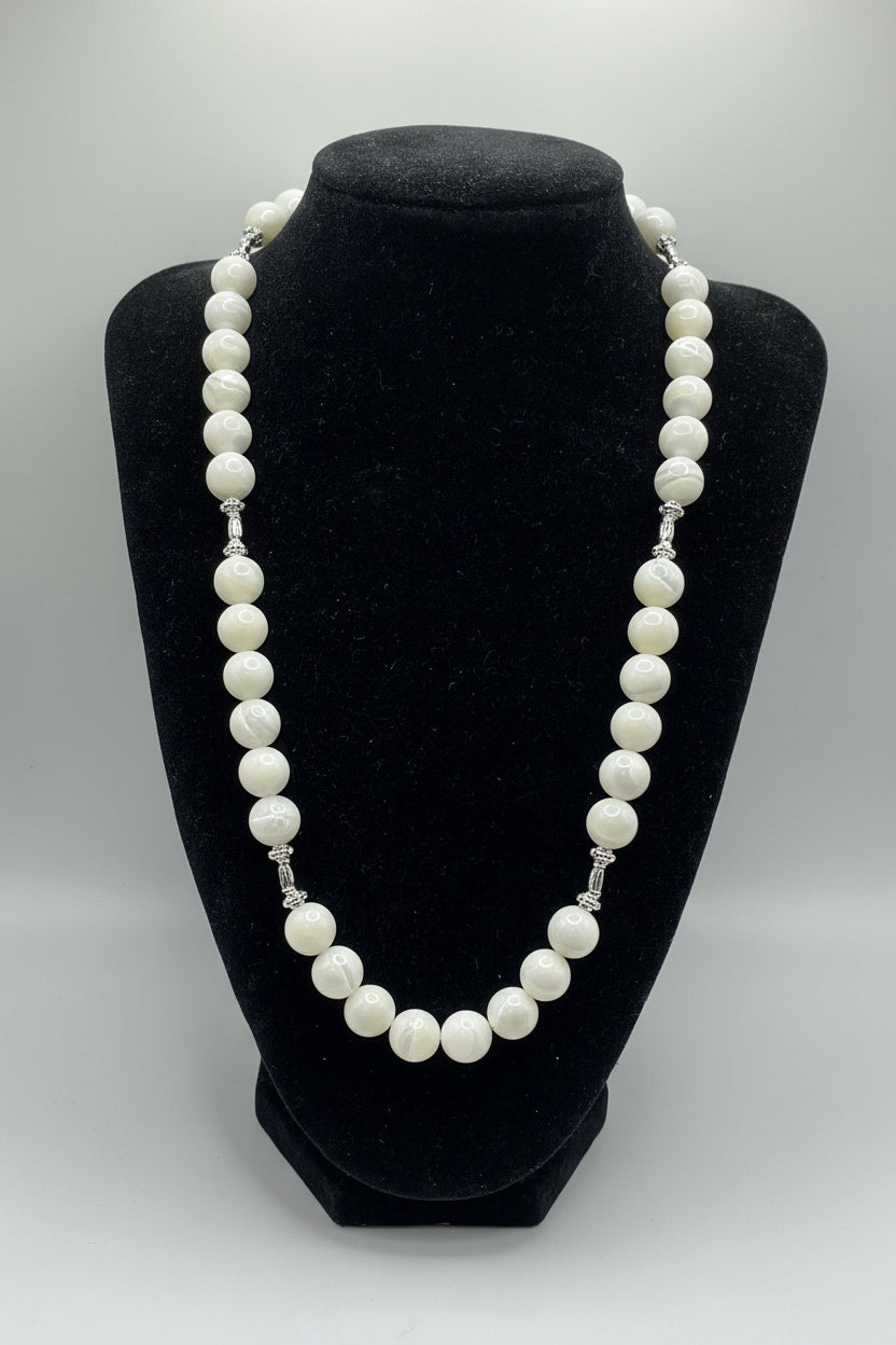 A white pearl necklace with silver-toned chain links, displayed on a black velvet jewelry bust against a light gray background.