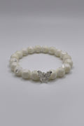 White beaded bracelet with a silver butterfly charm on a white background