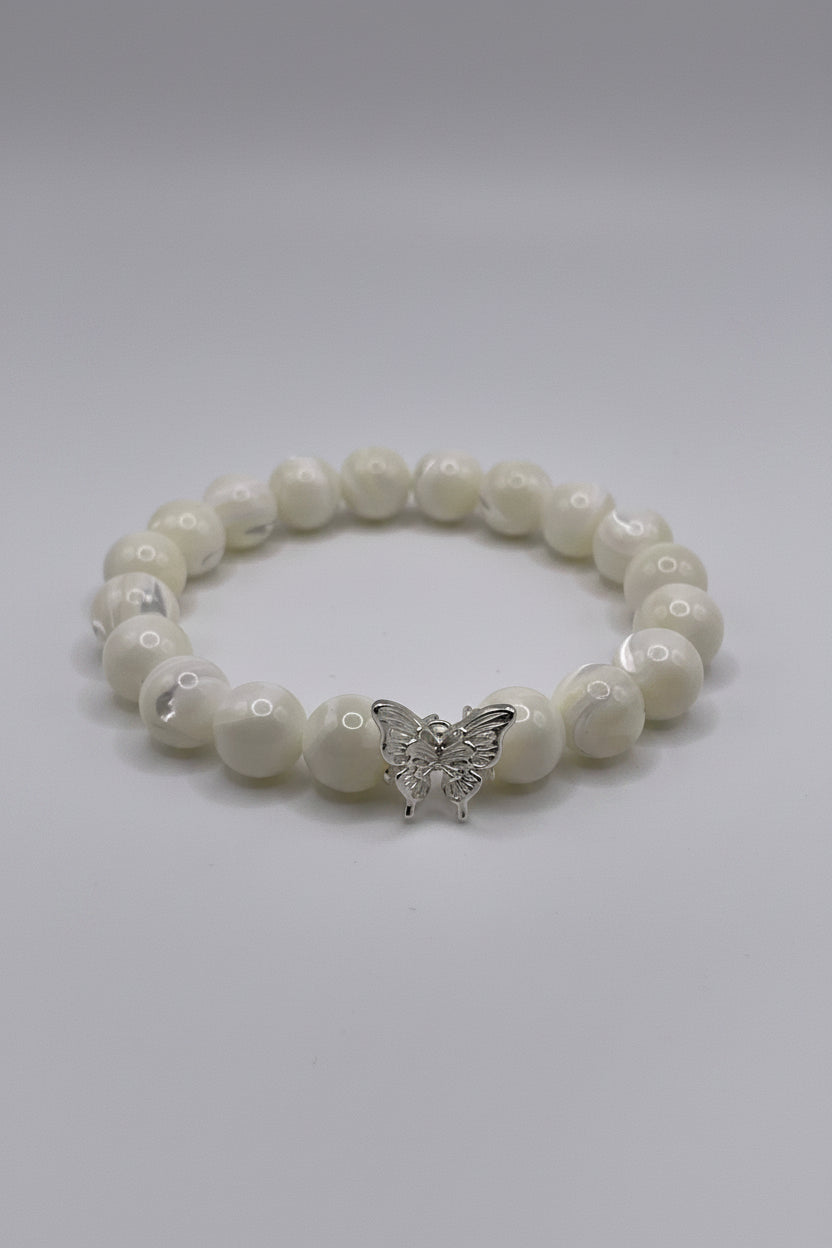White beaded bracelet with a silver butterfly charm on a white background