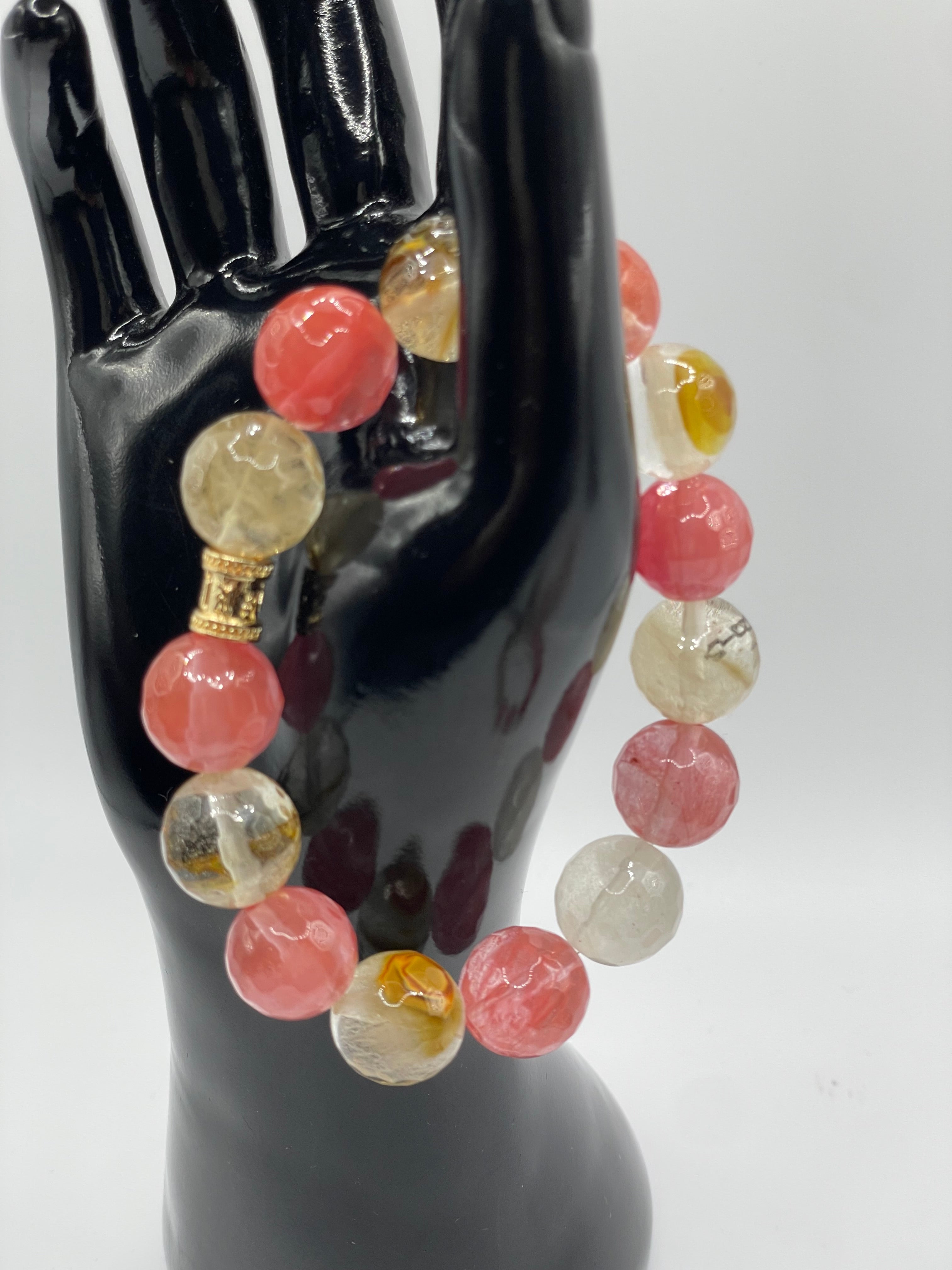 Multicolored beaded bracelet on a black mannequin hand against a white background