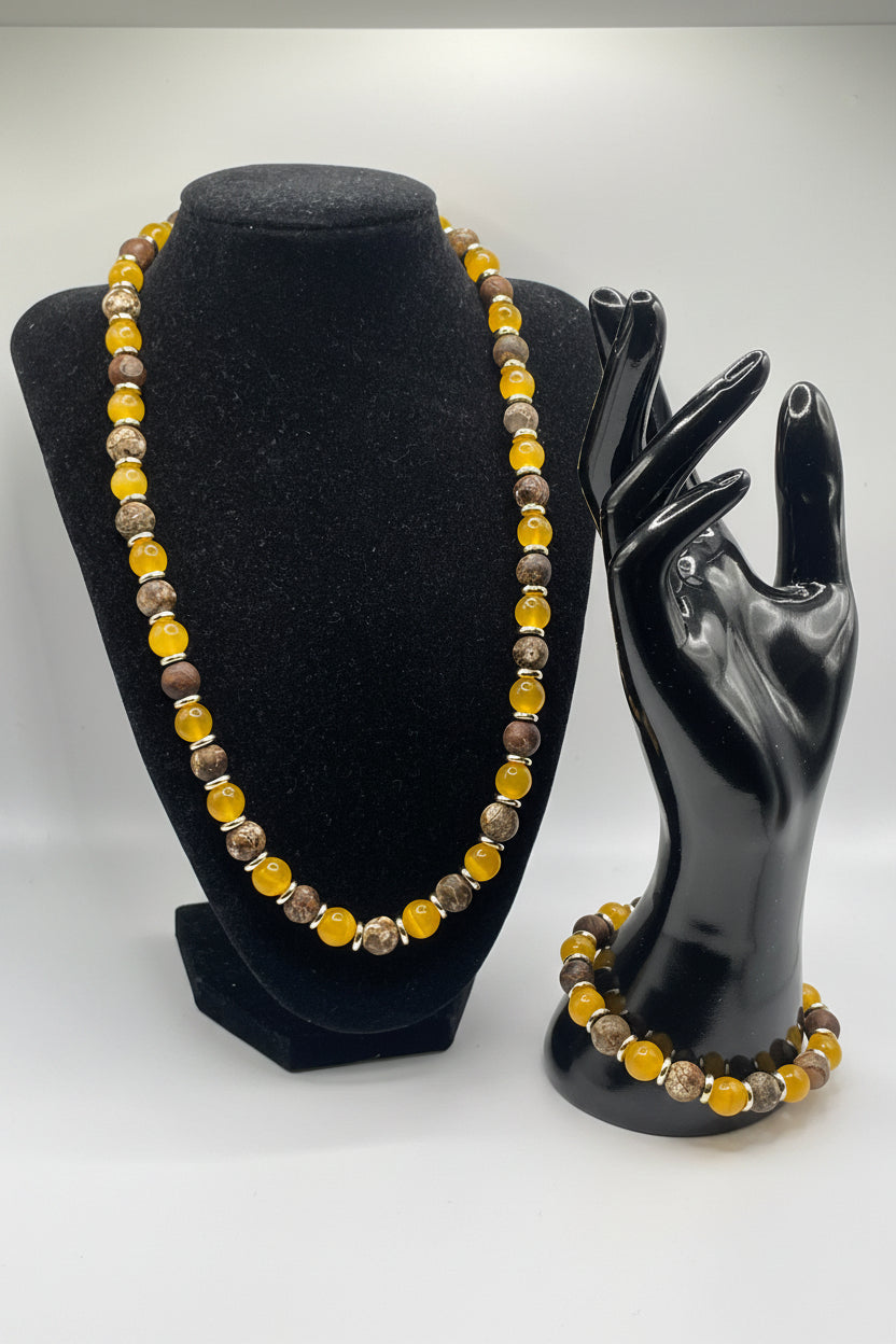 Black hand holding a beaded bracelet with yellow and brown beads on a white background