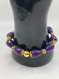 Purple beaded bracelet with gold accents on a black mannequin bust.