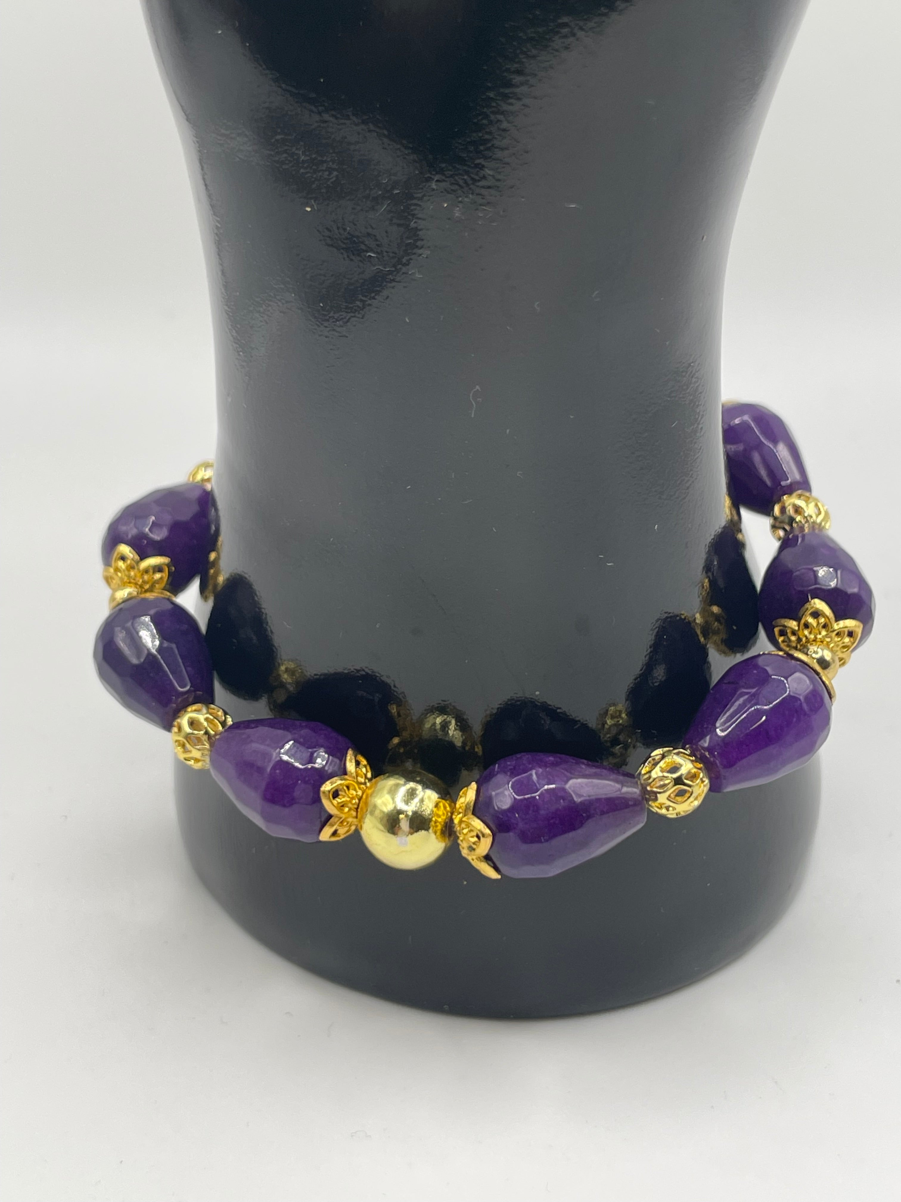Purple beaded bracelet with gold accents on a black mannequin bust.