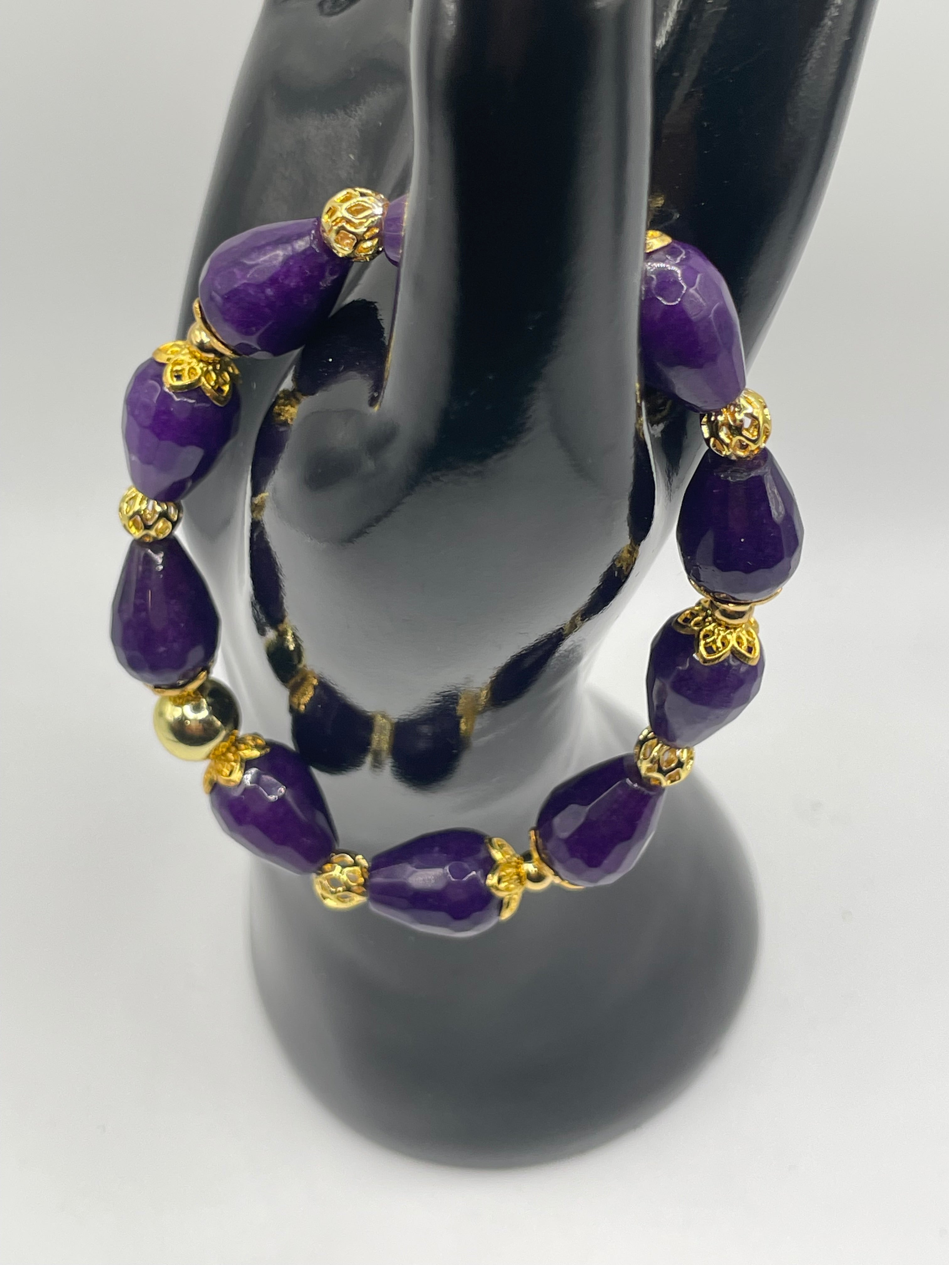 Purple beaded bracelet with gold accents on a black mannequin hand.
