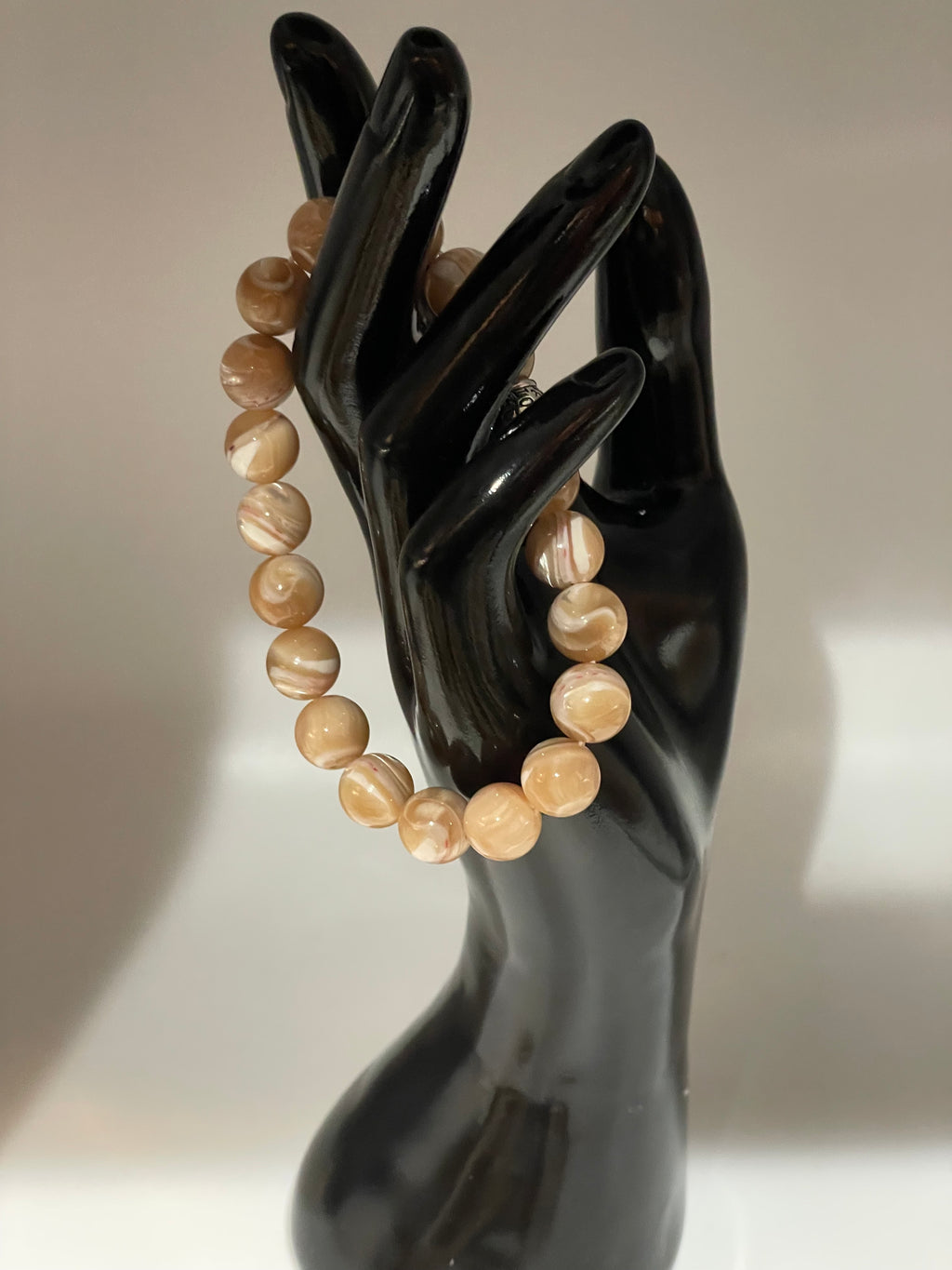 Beaded bracelet on a black mannequin hand against a neutral background