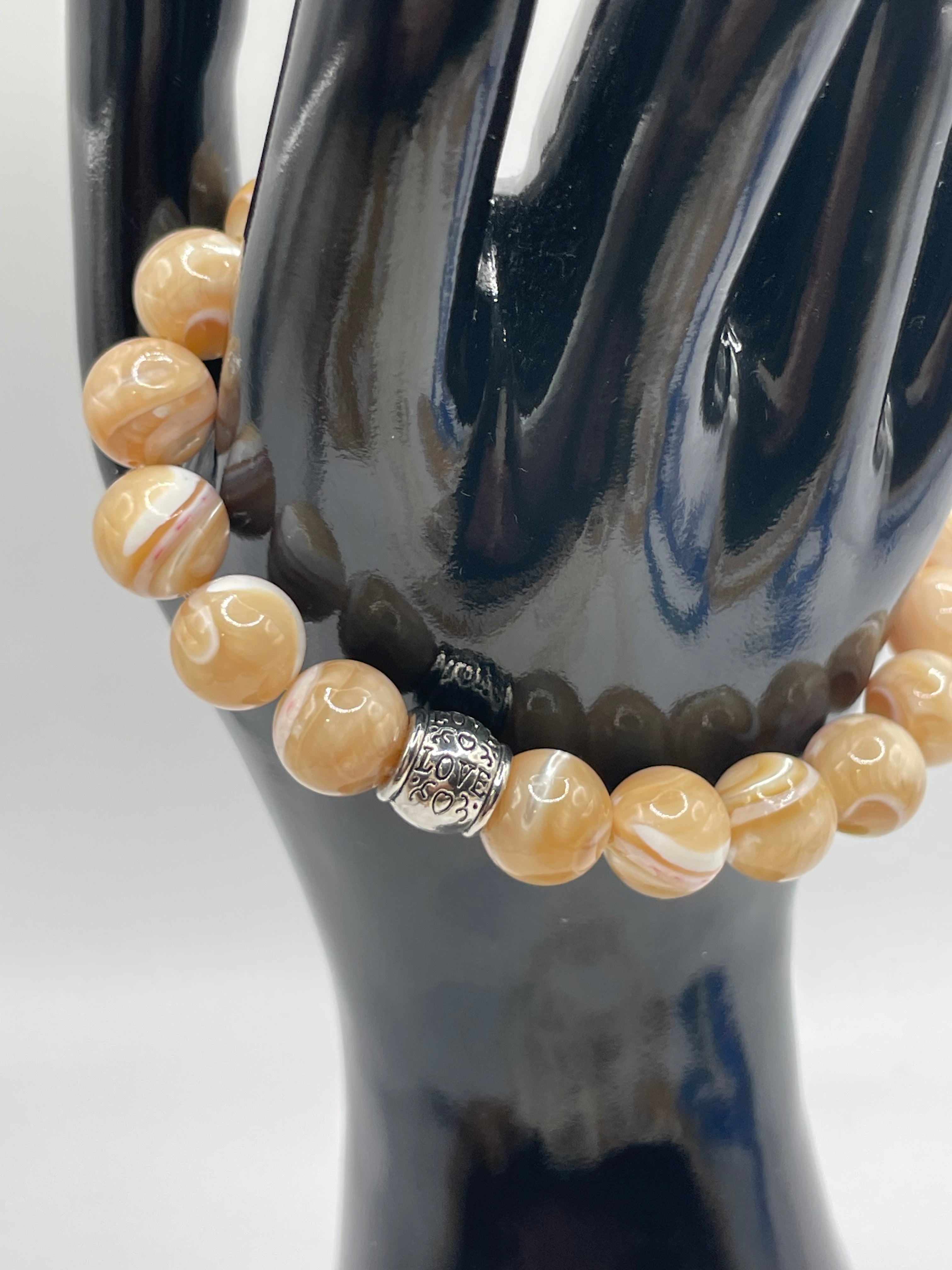 Beaded bracelet with a silver charm on a reflective surface