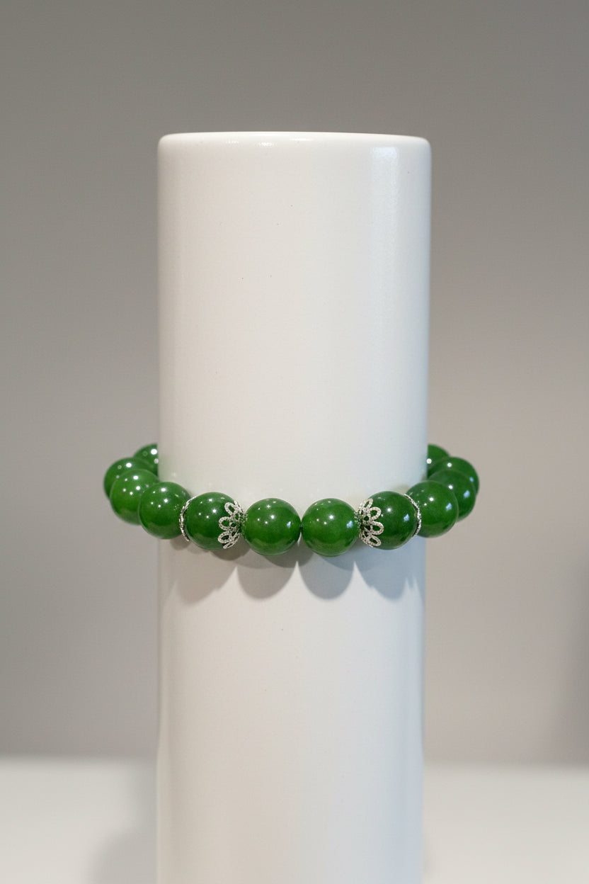 Green beaded bracelet with silver accents on a metallic surface