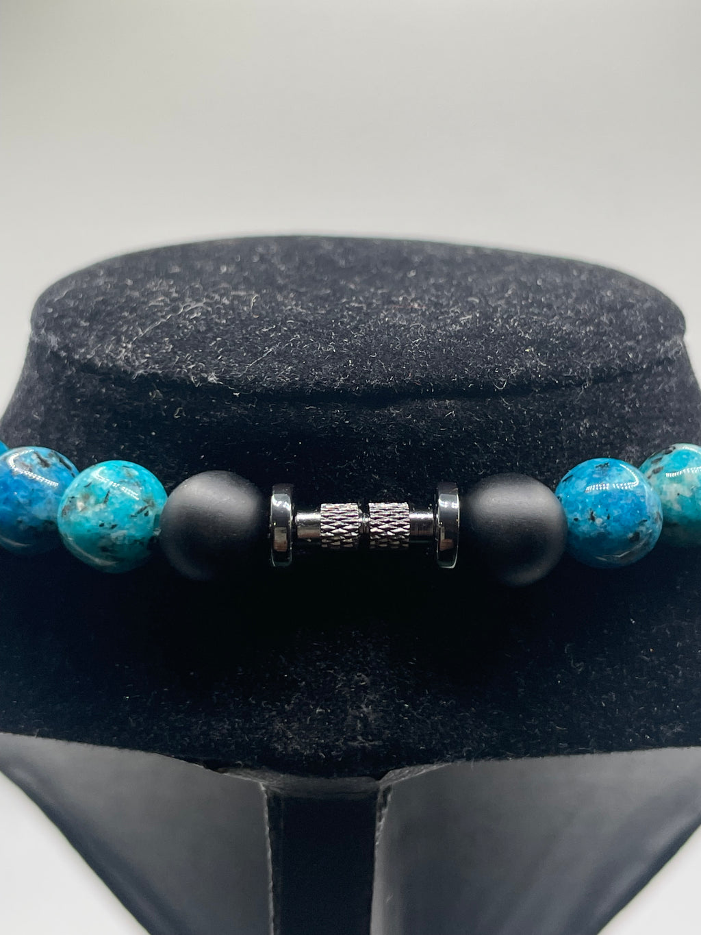 Close-up of a beaded bracelet with black and blue beads on a gray background