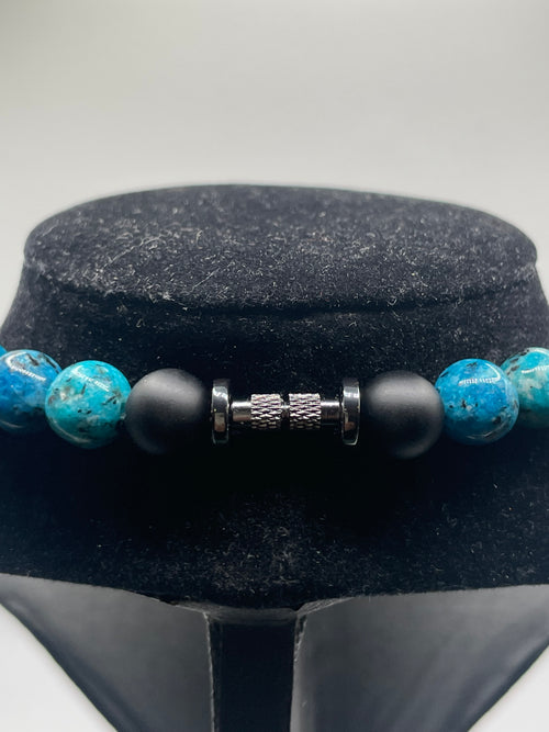 Close-up of a beaded bracelet with black and blue beads on a gray background