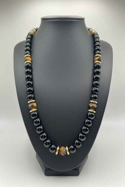 Necklace with black, gold, and clear beads on a gray bust
