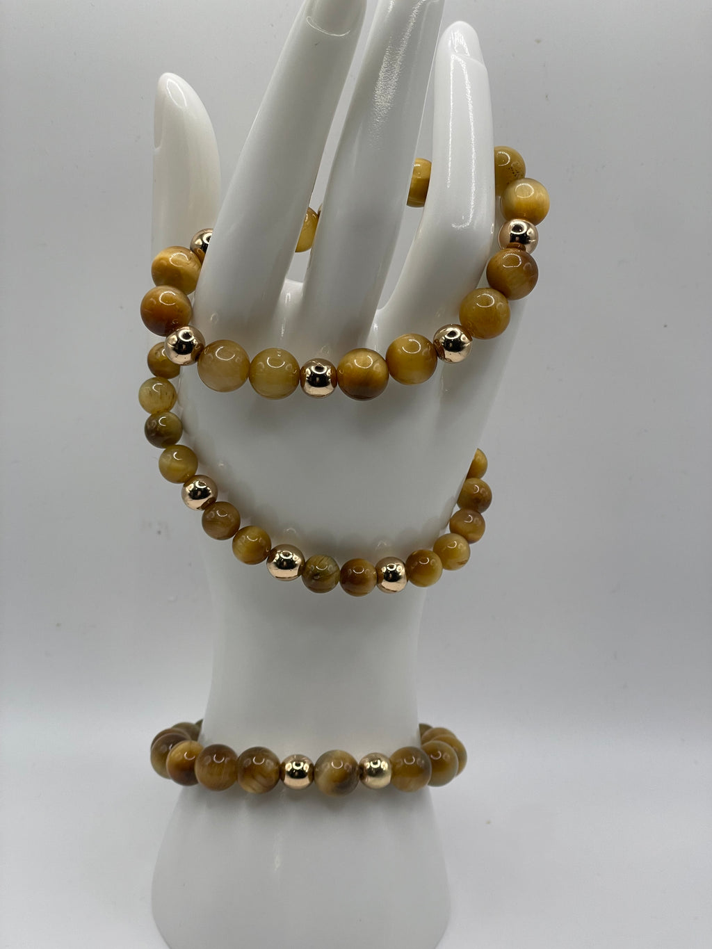 Beaded bracelet with gold accents on a mannequin hand against a white background