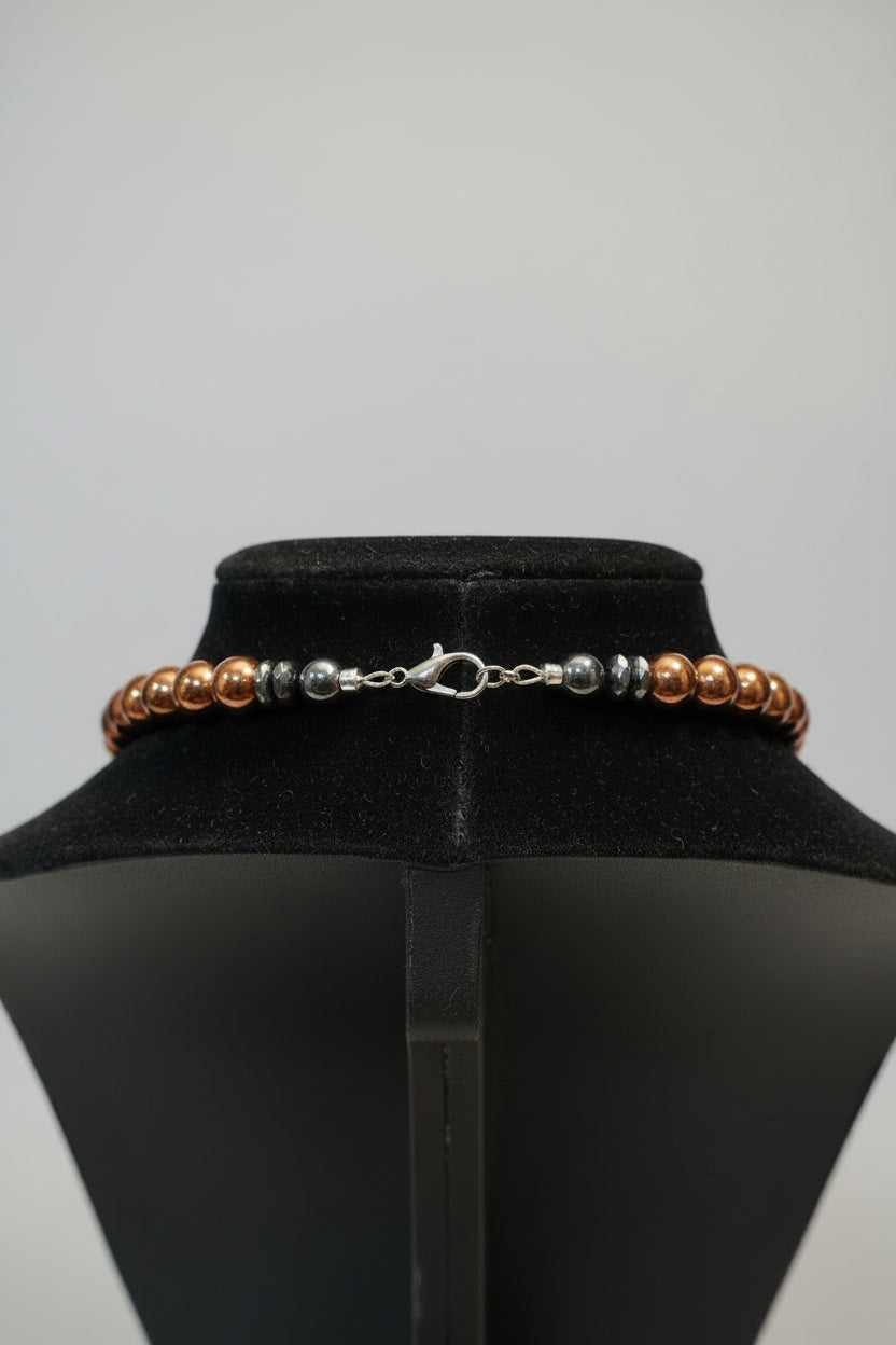 A beaded necklace back with brown and silver-toned beads displayed on a black velvet jewelry stand