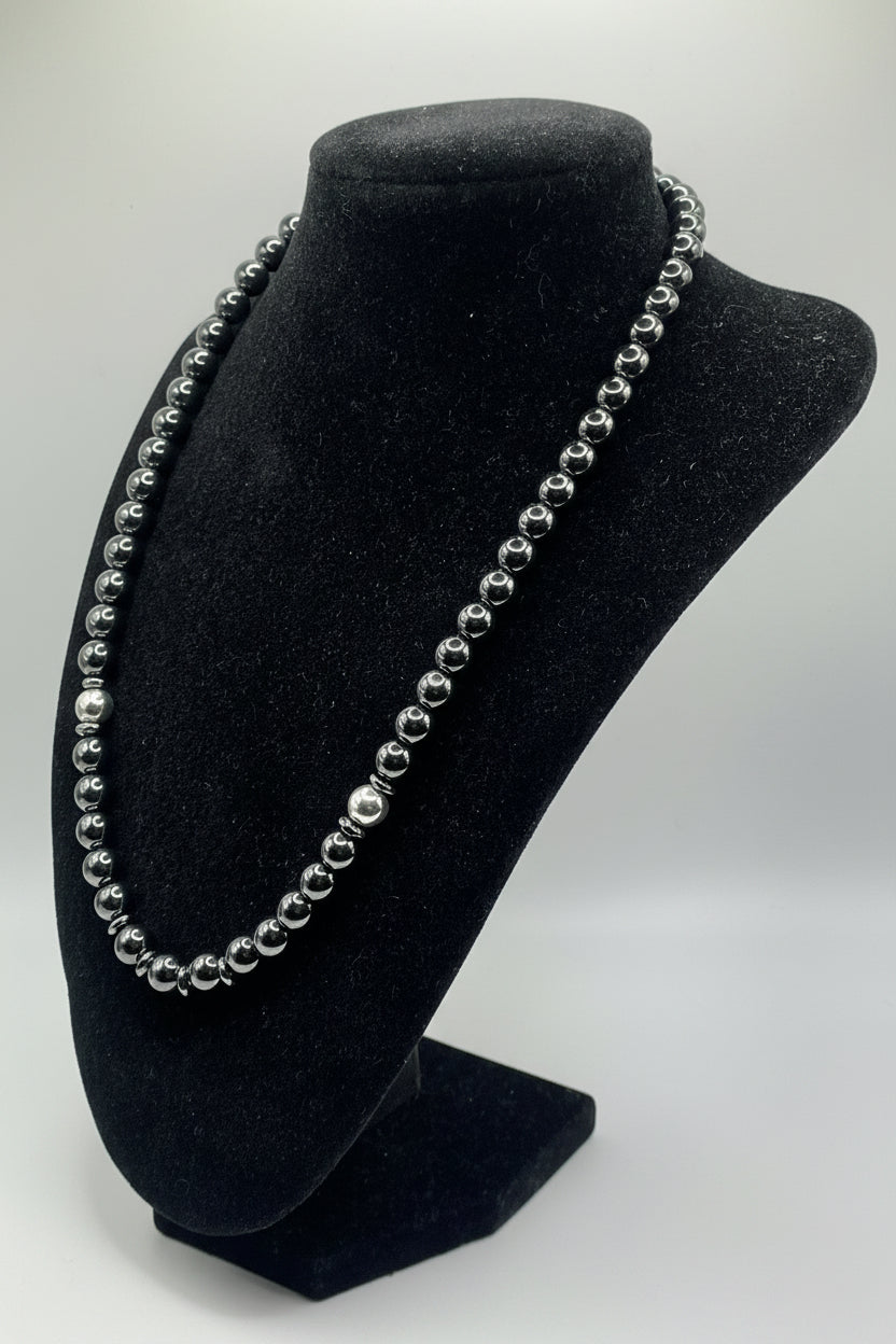 A black velvet jewelry display bust holding a silver beaded headband, photographed against a plain light gray background.