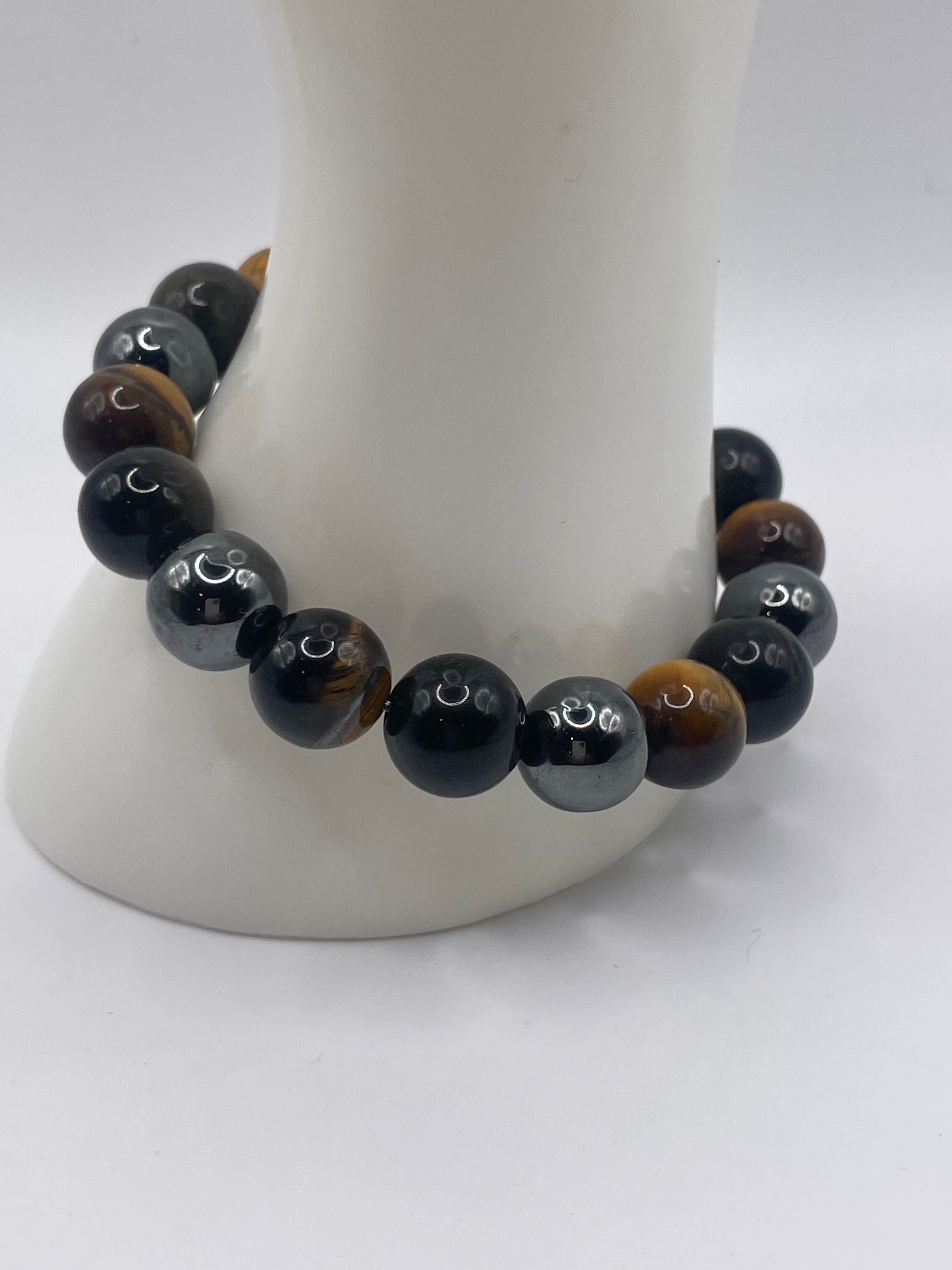 A beaded bracelet displayed on a white mannequin arm. The bracelet features glossy black beads with white crescent moon symbols and brown tiger's eye beads with natural brown stripes.