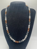 A beaded strand necklace with alternating silver and copper-colored round beads, displayed on a black velvet jewelry bust against a light gray background.