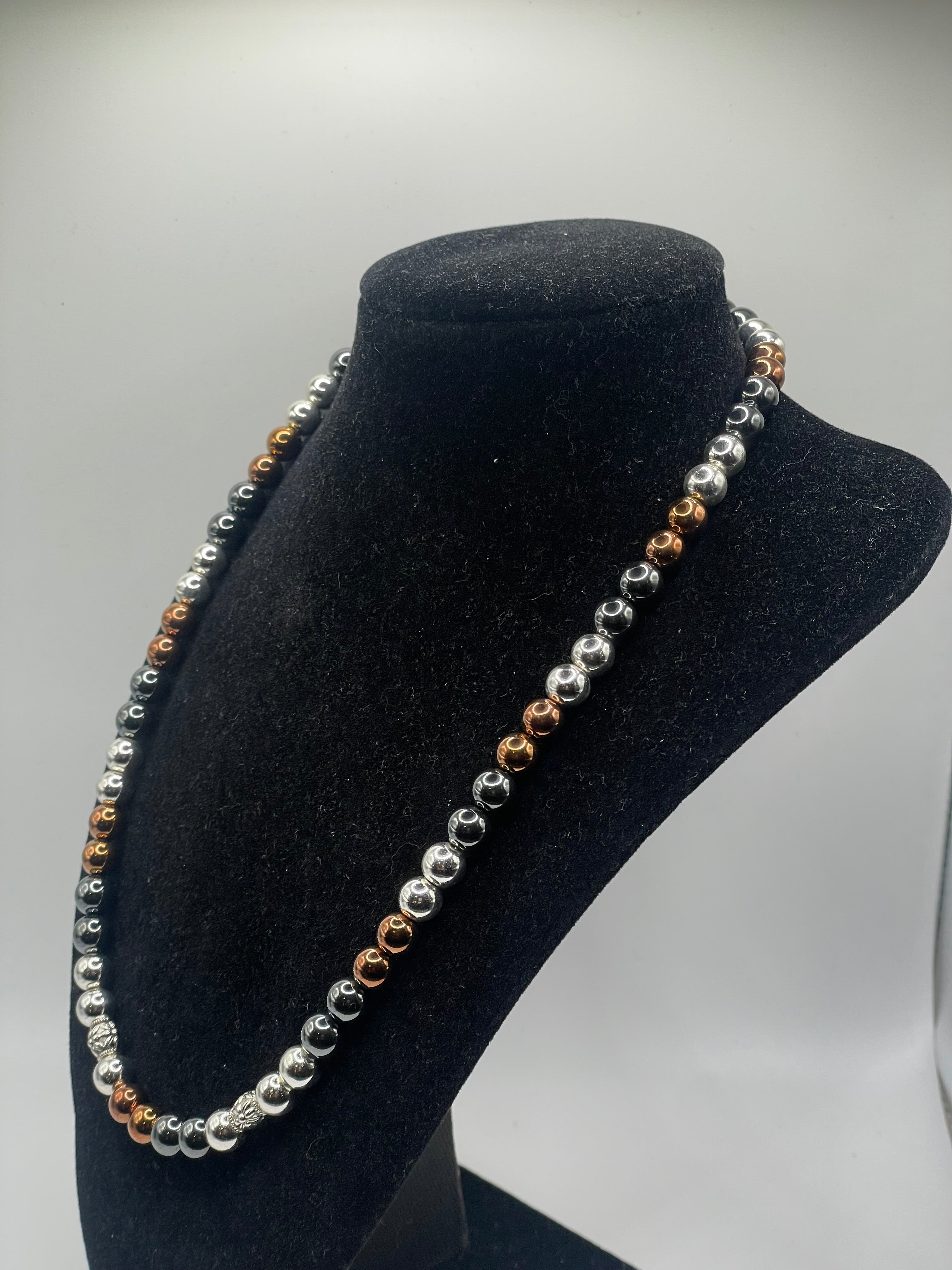 A beaded headband with alternating silver, white, and rose gold beads, displayed on a black velvet jewelry bust against a light gray background.