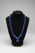 A beaded necklace made of polished dark blue lapis lazuli stones, displayed on a black velvet jewelry bust.