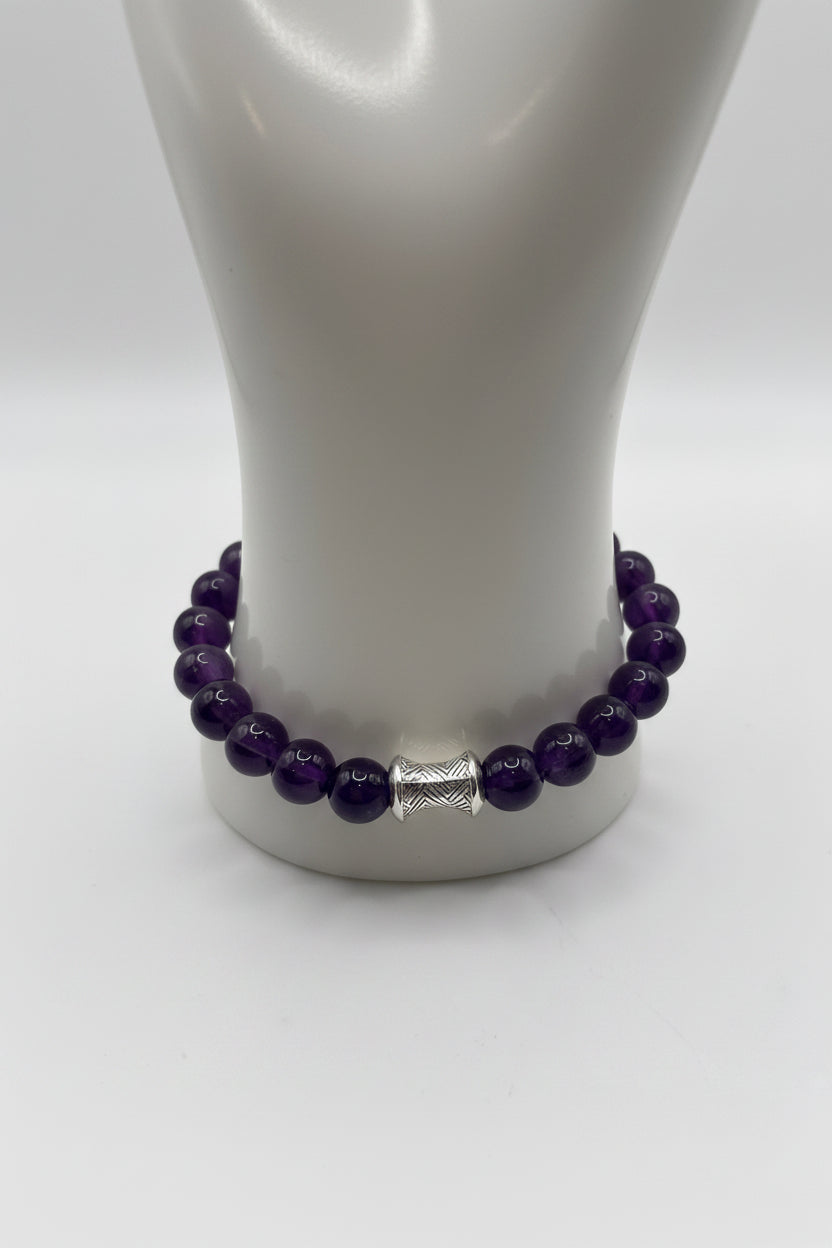Dark amethyst 10mm bead stretch bracelet with silver spiral barrel charm on display stand