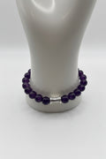 Dark amethyst 10mm bead stretch bracelet with silver spiral barrel charm on display stand