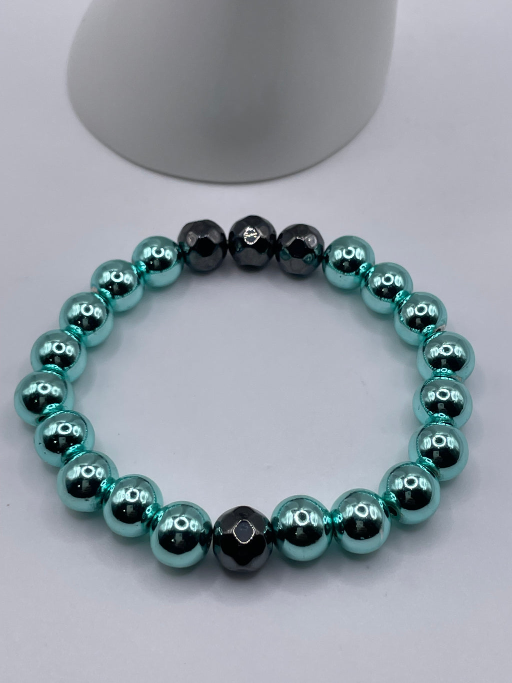 Cyan hematite and faceted black hematite stretch bracelet laid flat on white surface