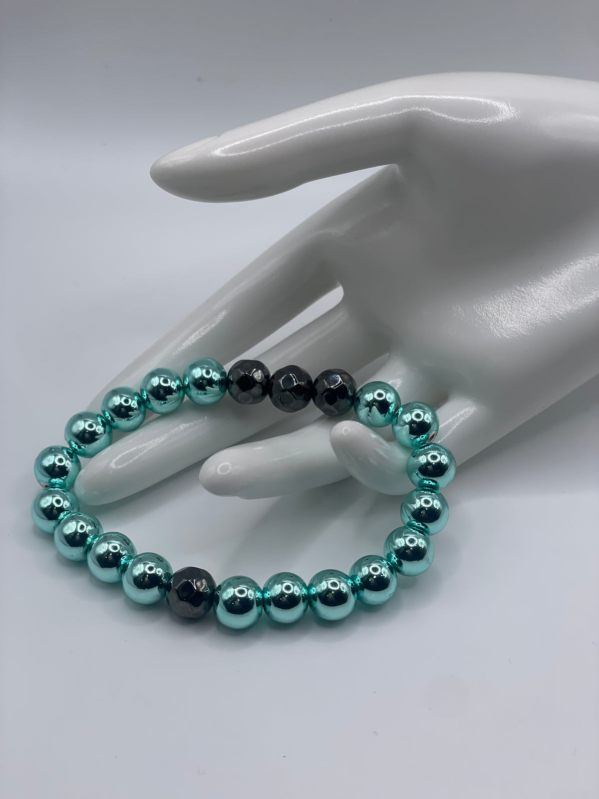 Cyan hematite and faceted black hematite bracelet worn on white hand mannequin