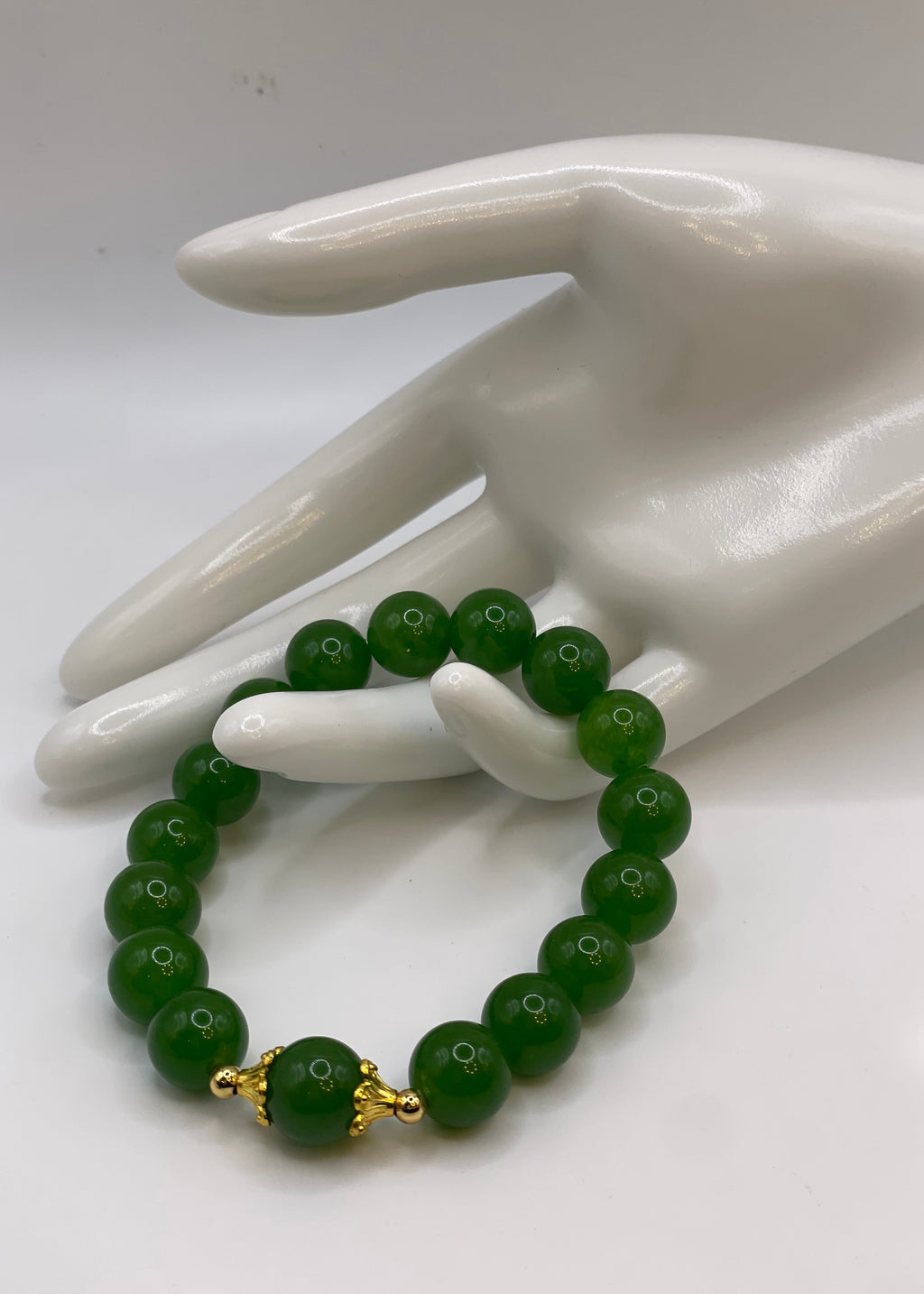 Raw jade bracelet with 18kt gold plated flower spacers on a white display hand