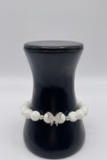 A beaded bracelet with white pearl-like round beads and a central silver butterfly charm, displayed on a black jewelry bust against a light gray background.