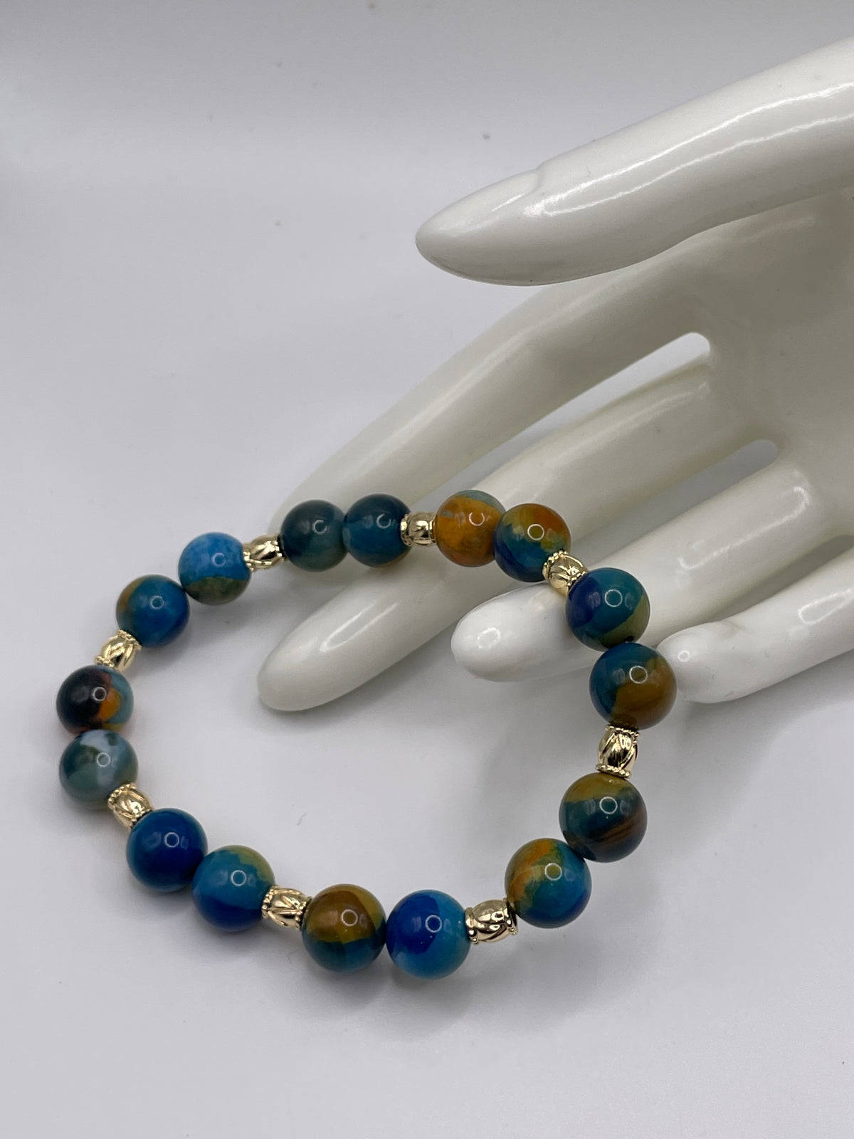 Blue and Yellow Agate Bead Bracelet 10mm with 8 gold spacers flat lay
