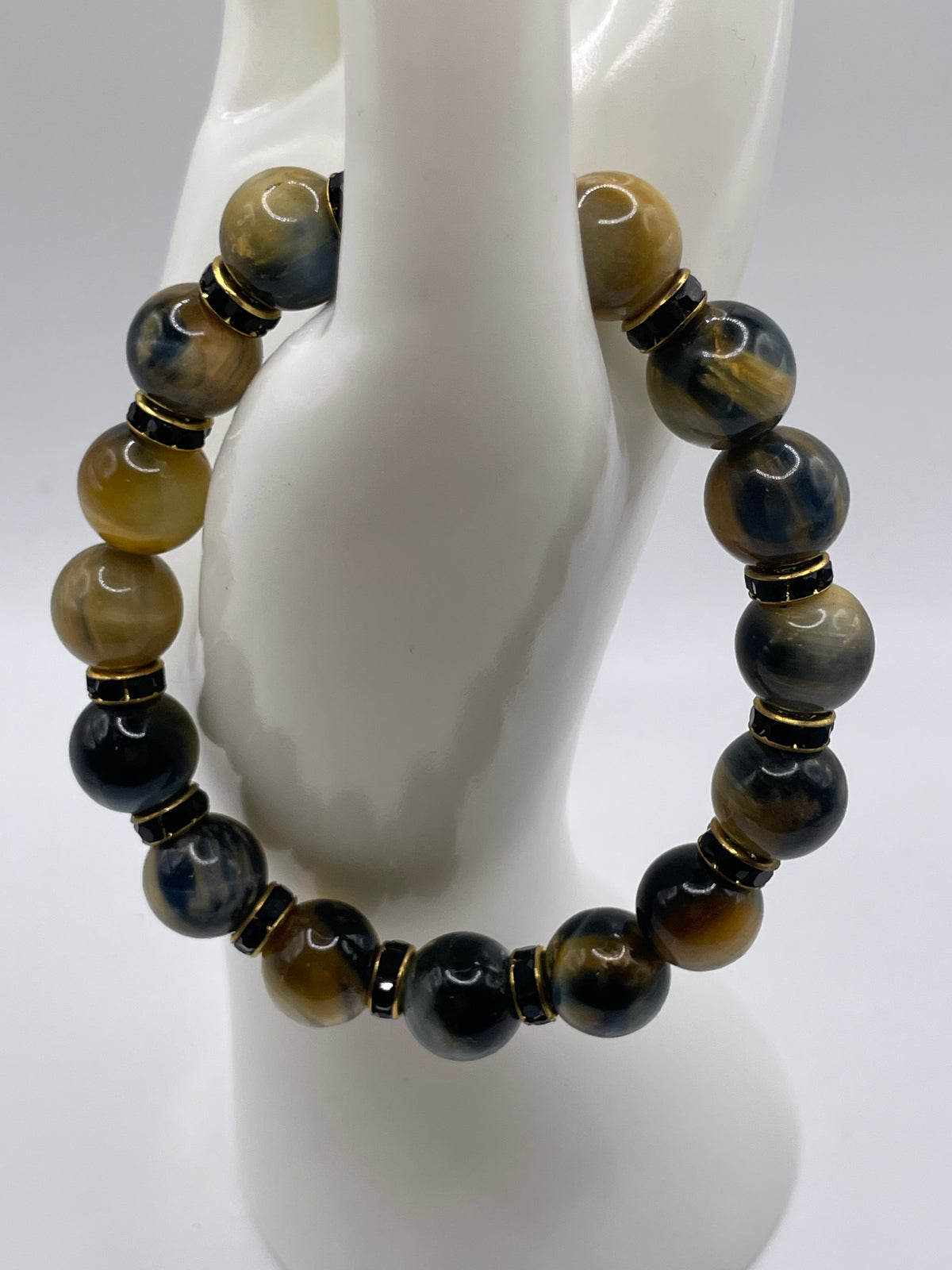12mm Dream Tiger Eye bracelet with black and gold rhinestone spacers overhead view on mannequin