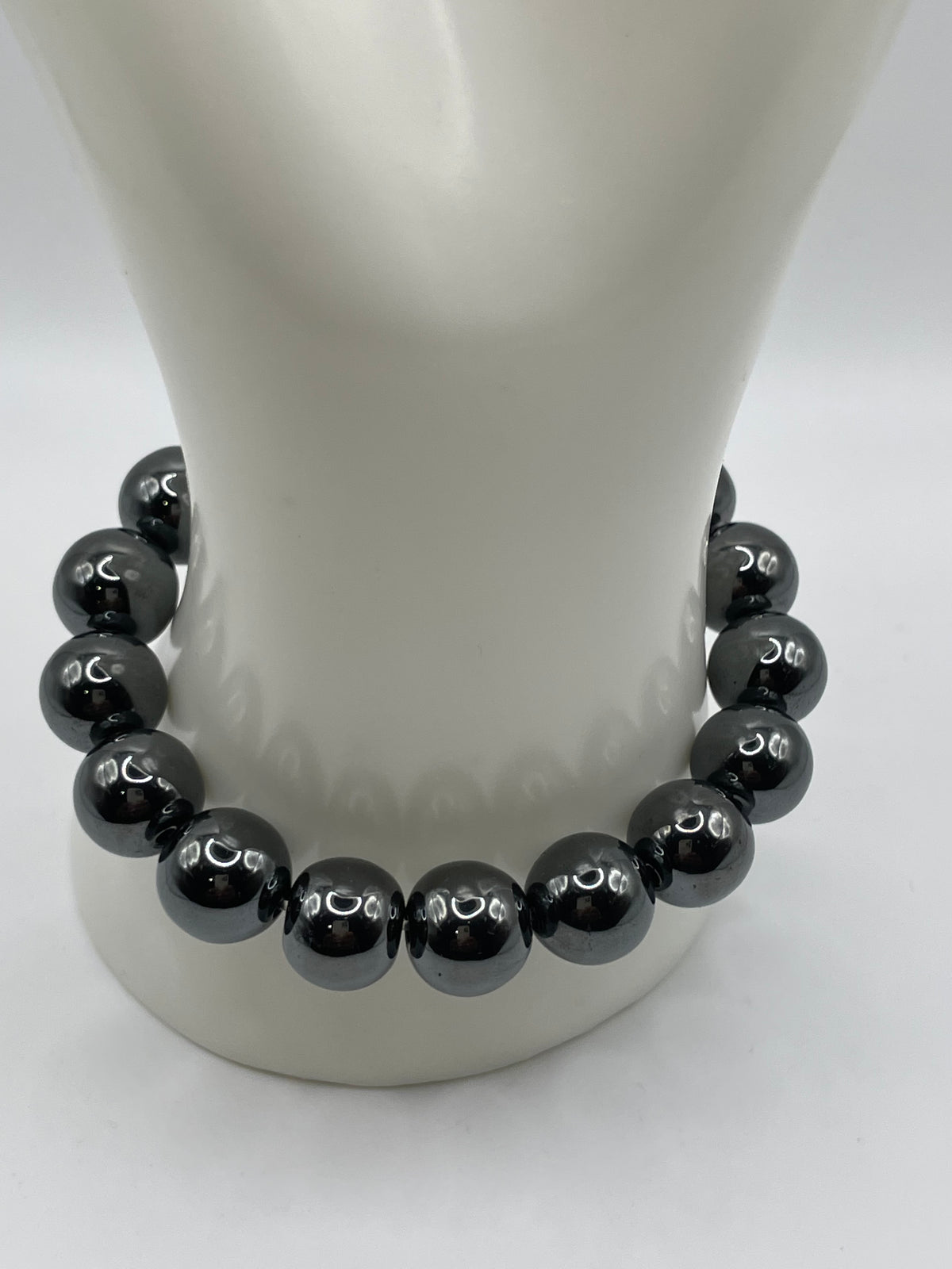 A beaded bracelet made of glossy black round beads with small white crescent moon symbols, displayed on a white mannequin bust against a white background.