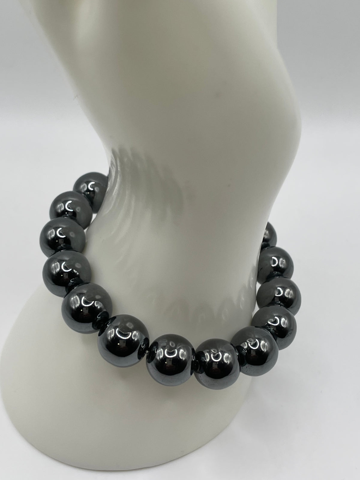 A beaded stretch bracelet made of glossy black round beads, displayed on a white mannequin neck against a white background.