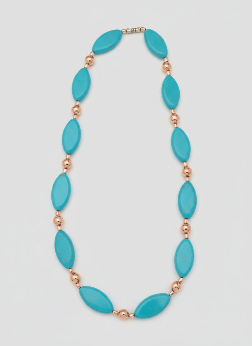 Necklace with blue oval beads and pink accents on a wooden surface