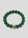 Green beaded bracelet with a silver charm on a wooden surface