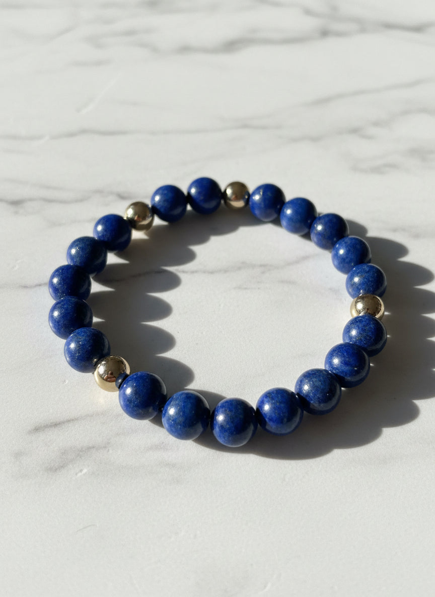 Blue beaded bracelet with gold accents on a marble surface