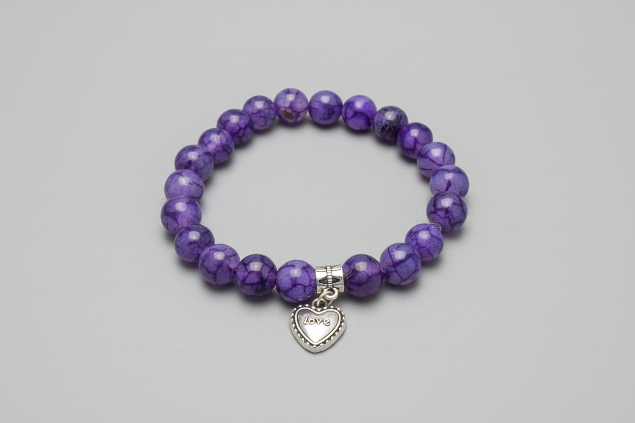 Purple beaded bracelet with a silver heart charm on a wooden surface