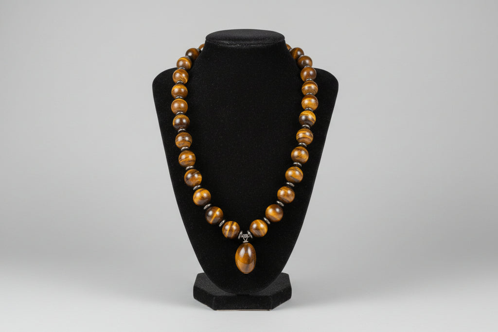 Bracelet with brown beads on a black stand against a blurred indoor background