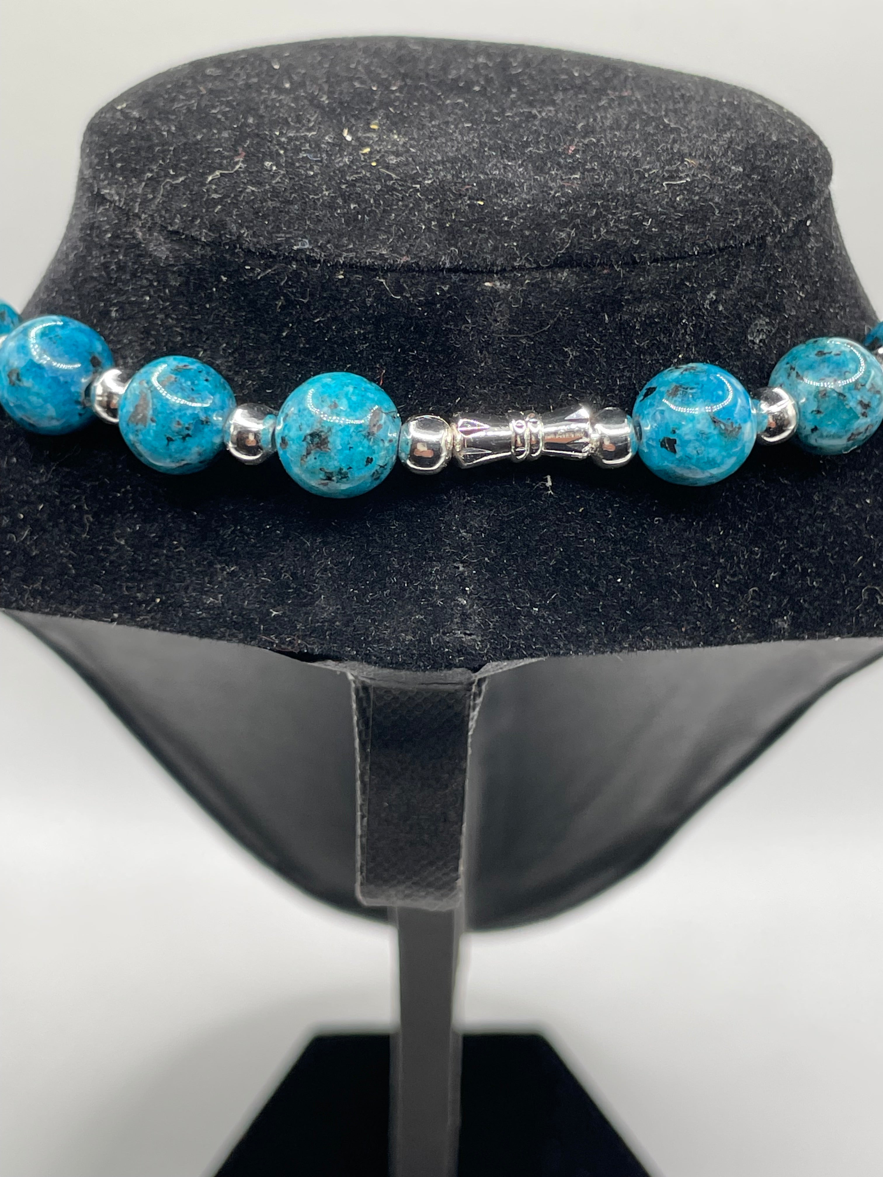 Blue Spotted jasper beaded necklace back clasps silver accents on a black stand.