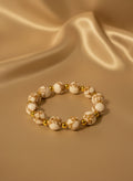 Bracelet with white and gold beads on a beige fabric background
