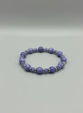 Purple beads with a gold heart and gold spacers bracelet on a wooden surface