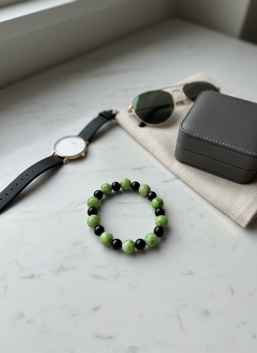 Bracelet with green and black beads on a beige fabric background