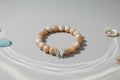Beaded bracelet with a silver butterfly charm on a wooden surface