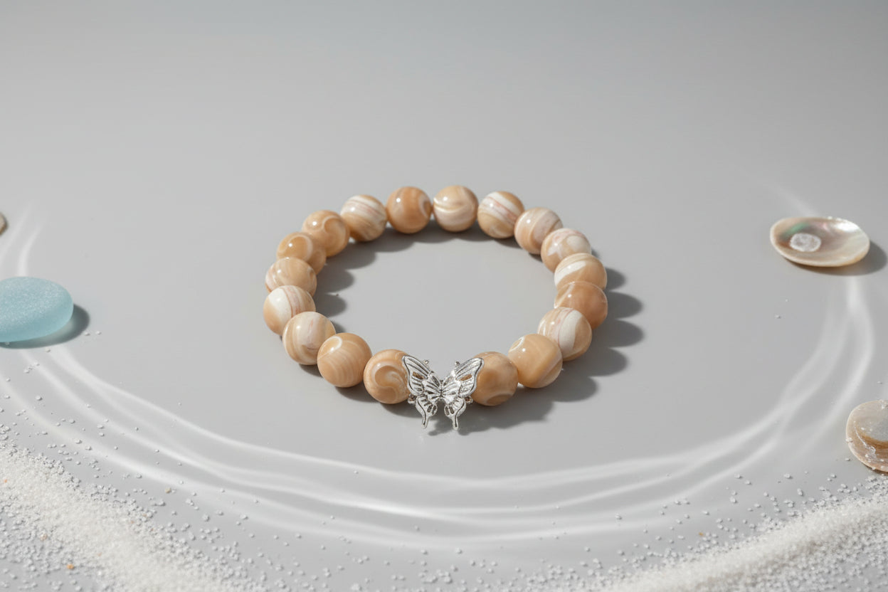 Beaded bracelet with a silver butterfly charm on a wooden surface