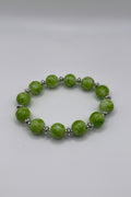 Green beaded bracelet with silver accents on a beige background