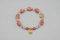 Bracelet with pink beads and a gold heart charm on a wooden surface