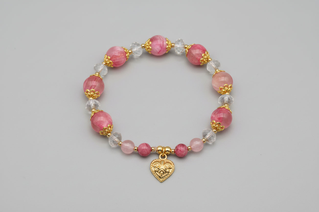 Bracelet with pink beads and a gold heart charm on a wooden surface